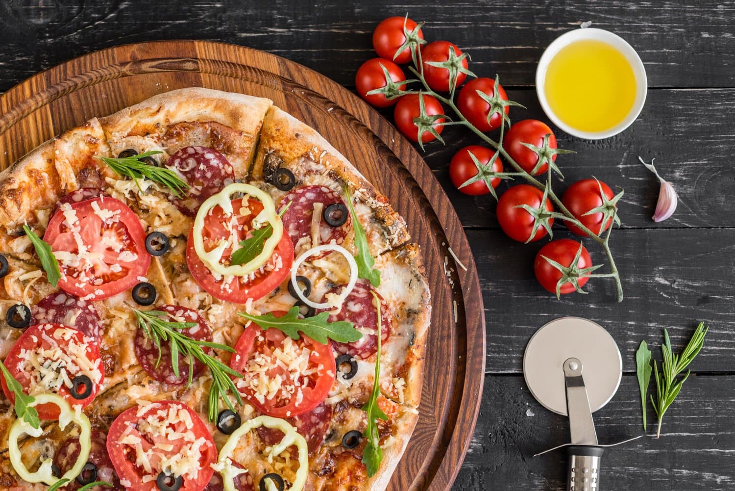 a wooden plate with a pizza and small red tomatoes