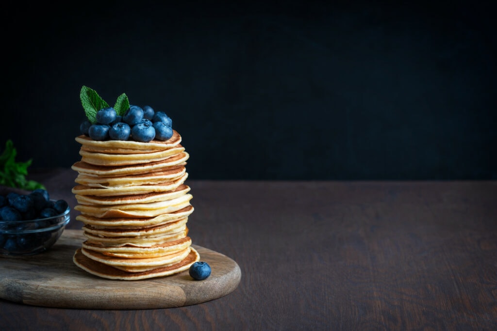 a stack of pancakes with blue berries on top