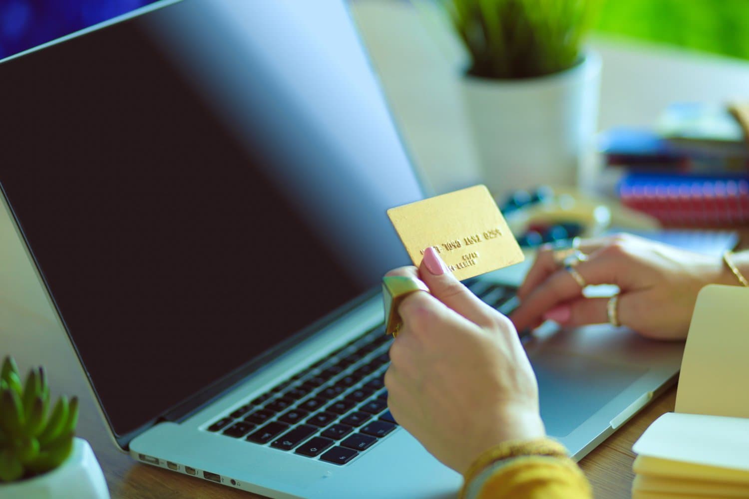 a lady using her laptop with a golden card in her hand