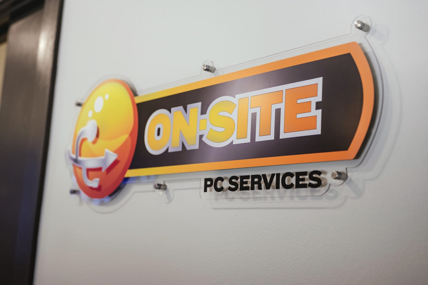 Yellow and Orange w/ black background On-Site PC Services office wall sign bolted to the wall