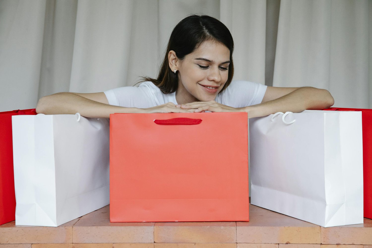 Excited young female leaning on shopping bags and smiling happily